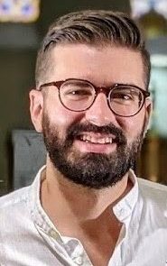 A man with glasses and beard smiling for the camera.